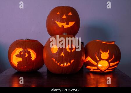 Vier beleuchtete Jack O Laterne geschnitzte Kürbisse glühen an Halloween Nacht Stockfoto