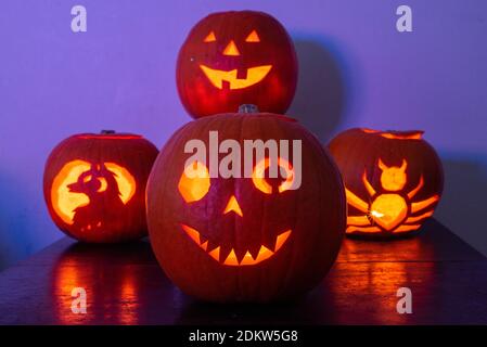 Vier beleuchtete Jack O Laterne geschnitzte Kürbisse glühen an Halloween Nacht Stockfoto