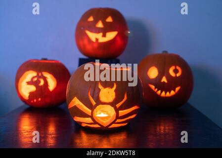 Vier beleuchtete Jack O Laterne geschnitzte Kürbisse glühen an Halloween Nacht Stockfoto