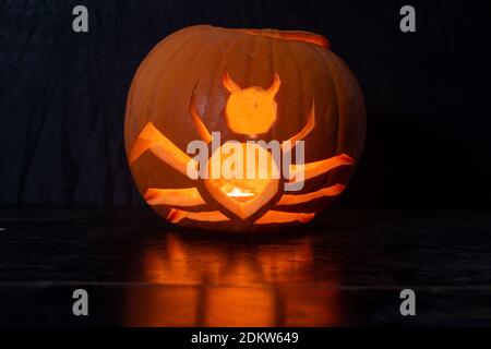 Ein Jack O Laterne Kürbis geschnitzt in der Form von Eine Spinne, die in der Halloween-Nacht leuchtet Stockfoto