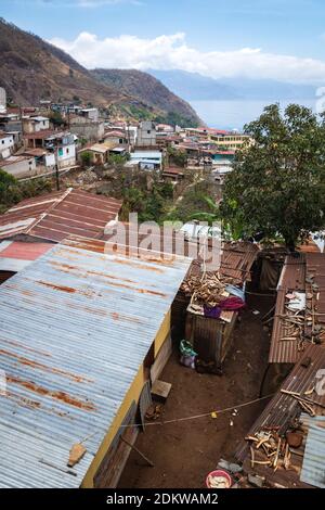 Local houses with rusty tin roofs and wood on top in steep mountain village along lake Atitlan, Santa Cruz la Laguna, Guatemala Stock Photo