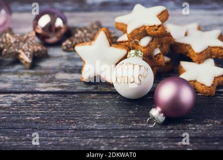 weihnachtshintergrund für Grußkarten mit Kopierraum, Zimt Sterne neben einem weihnachtsball auf Holzhintergrund Stockfoto