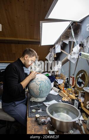 Eine Menschenhand malt bei Bellerby & Co Globemakers in Stoke Newington, London, Großbritannien, einen Globe Atlas, den größten handgefertigten Globus der Welt mit einem Durchmesser von 50 cm Stockfoto