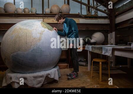 Eine Menschenhand malt einen Chruchill Globe, den größten handgefertigten Globus der Welt mit einem Durchmesser von 50 cm, bei Bellerby & Co in Stoke Newington, North London, UK Stockfoto