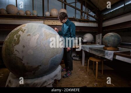 Eine Menschenhand malt einen Chruchill Globe, den größten handgefertigten Globus der Welt mit einem Durchmesser von 50 cm, bei Bellerby & Co in Stoke Newington, North London, UK Stockfoto