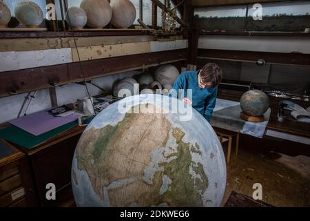 Eine Menschenhand malt einen Chruchill Globe, den größten handgefertigten Globus der Welt mit einem Durchmesser von 50 cm, bei Bellerby & Co in Stoke Newington, North London, UK Stockfoto