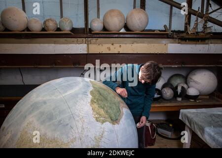 Eine Menschenhand malt einen Chruchill Globe, den größten handgefertigten Globus der Welt mit einem Durchmesser von 50 cm, bei Bellerby & Co in Stoke Newington, North London, UK Stockfoto