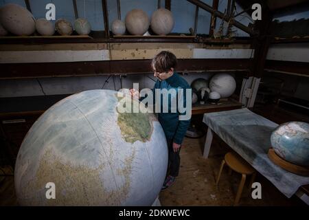 Eine Menschenhand malt einen Chruchill Globe, den größten handgefertigten Globus der Welt mit einem Durchmesser von 50 cm, bei Bellerby & Co in Stoke Newington, North London, UK Stockfoto