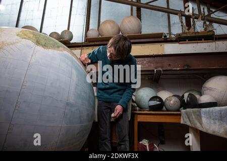 Eine Menschenhand malt einen Chruchill Globe, den größten handgefertigten Globus der Welt mit einem Durchmesser von 50 cm, bei Bellerby & Co in Stoke Newington, North London, UK Stockfoto