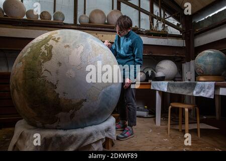 Eine Menschenhand malt einen Chruchill Globe, den größten handgefertigten Globus der Welt mit einem Durchmesser von 50 cm, bei Bellerby & Co in Stoke Newington, North London, UK Stockfoto