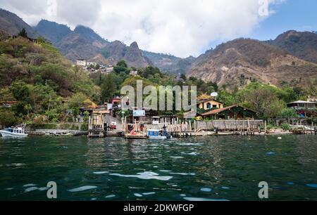 View from lake Atitlan to the coast with boat docks of the green mountain village Santa Cruz la Laguna, Guatemala Stock Photo