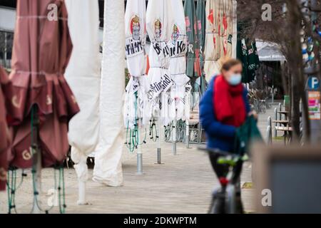 Berlin, Deutschland. Dezember 2020. Eine Frau mit Mund-Nase-Schutz geht an geschlossenen Sonnenschirmen von Restaurants in der Nähe der Friedrichstraße entlang. Quelle: Christoph Soeder/dpa/Alamy Live News Stockfoto