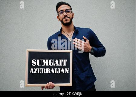Araber tragen blaues Hemd und Brillen halten Brett mit Sumgait Aserbaidschan Inschrift. Größte Städte in der islamischen Welt Konzept. Stockfoto