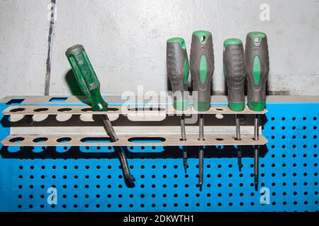 Ein Satz schmutziger grüner Schraubendreher hängt in der Garage Stockfoto