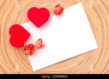 Zwei rote Herzen und trockene Blumen auf weißem Blatt, Layout, Platz für Text. Postkarte für Valentinstag oder Hochzeitsfeier Stockfoto