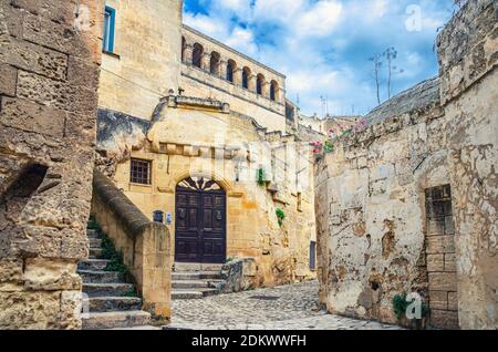 Straße mit alten Steinhäusern und Gebäuden in Sassi di Matera historischen Zentrum Sasso Caveoso, alte Stadt mit Felshöhlenhäusern, blauen Himmel und w Stockfoto