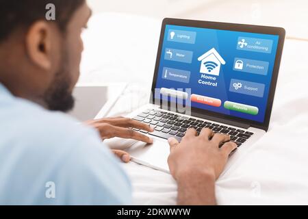 Black Man Mit Laptop Mit Smart Home Control System Auf Dem Bildschirm, Collage Stockfoto