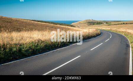 Der Leuchtturm South Downs und Belle Tout, Sussex, England. Eine kurvige Straße, die zur Küste des Ärmelkanals führt und den Leuchtturm Belle Tout sichtbar macht. Stockfoto