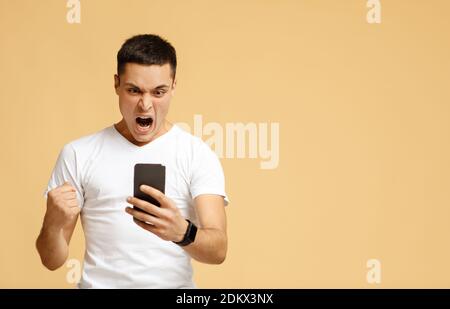 Aufgeregt Millennial Blogger aufgeregt schreit und sieht in Smartphone Stockfoto