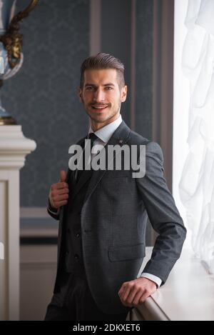 Bräutigam am Hochzeitstag lächelnd und wartet auf Braut in der Halle des Hotels. Elegant reicher Mann in Kostüm und Fliege. Stockfoto