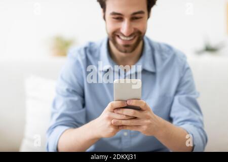Happy Guy Mit Smartphone Texting Sitzen Auf Der Couch Zu Hause Stockfoto