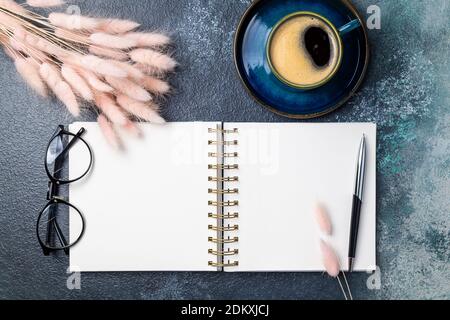 Offene weiße leere Notebook, Kaffeetasse, rosa getrocknete Blumen Blumenstrauß auf Schreibtisch des Home Office Wohnung lag. Freiberuflich, Blogging, feminin, Arbeitskonzept top Stockfoto