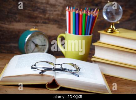 Öffnen Sie Tutorial mit Brille auf dem Tisch im Publikum. Bildungskonzept - Bücher auf dem Schreibtisch im Auditorium. Auf einem hölzernen Hintergrund. Selektiv fo Stockfoto