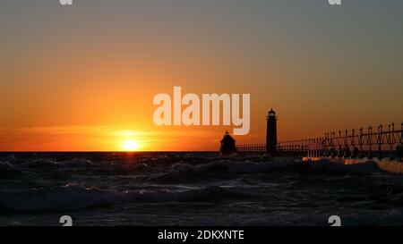 Grand Haven South Pier Leuchtturm bei Sonnenuntergang am Lake Michigan, an einem windigen Tag Stockfoto