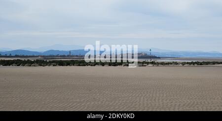 Blick in Richtung Rhyl, Wales von einem leeren Strand bei Ebbe mit Snowdonia dahinter. Stockfoto