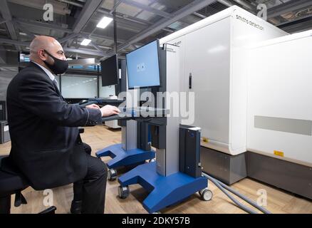 14. Dezember 2020, Hessen, Frankfurt/Main: Ein Sicherheitsmitarbeiter simuliert die Funktion eines CT-Gepäckscanners bei der Passagierabfertigung am Frankfurter Flughafen. Die Geräte sollen in der Lage sein, den Inhalt des Fluggepäcks in kürzester Zeit dreidimensional zu erfassen und gefährliche Stoffe weitgehend automatisch zu erkennen. (Zur dpa 'Bundespolizei testet CT-Gepäckscanner am Flughafen' von 16.12.20) Foto: Boris Roessler/dpa Stockfoto