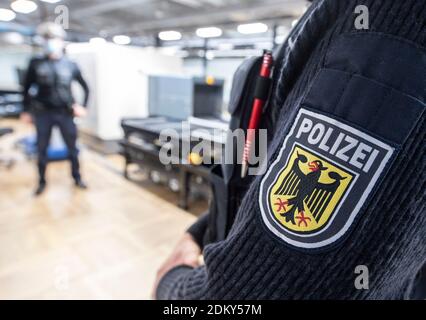 14. Dezember 2020, Hessen, Frankfurt/Main: Beamte der Bundespolizei stehen bei der Passagierabfertigung am Frankfurter Flughafen an einem CT-Gepäckscanner. Die Geräte sollen in der Lage sein, den Inhalt des Fluggepäcks in kürzester Zeit dreidimensional zu erfassen und gefährliche Stoffe weitgehend automatisch zu erkennen. (Zur dpa 'Bundespolizei testet CT-Gepäckscanner am Flughafen' von 16.12.20) Foto: Boris Roessler/dpa Stockfoto