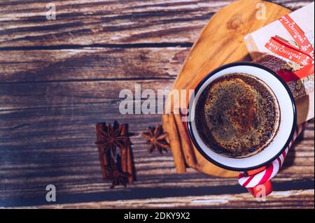 Schwarzer Kaffee in roter Tasse und weihnachtsschmuck auf Holzhintergrund. Draufsicht, Platz für Text. Weihnachten Hintergrund. Schwarzes Kaffeeposter. Stockfoto