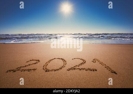 Happy New Year 2021 Konzept, Schriftzug am Strand. Geschriebener Text am Strand bei Sonnenaufgang. Stockfoto