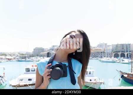 Lächelndes stilvolles Mädchen im venezianischen Hafen von Heraklion Kreta Griechenland. Elegantes Mädchen in türkisfarbenem Kleid und Kamera auf einem Spaziergang Sightseeing-Reise. Veneti Stockfoto