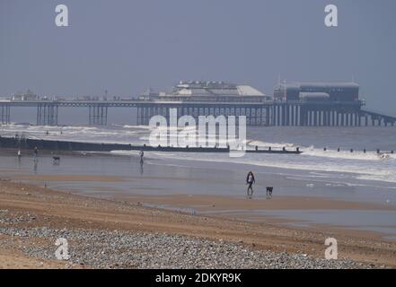 Cromer Beach und sein berühmter Pier in einem leichten atmosphärischen Dunst, mit Hundespaziergängern, Cromer, North Norfolk, England, VEREINIGTES KÖNIGREICH Stockfoto