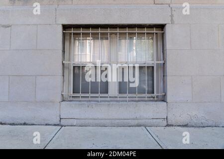 Kellerfenster mit Metallstangen, grauer Stein außen, Gehweg, horizontales Aussehen Stockfoto