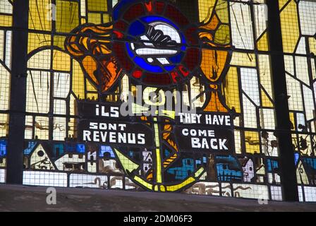 Ein Buntglasfenster in der Kirche von Sainte-Mere-Eglise, berühmt für einen Fallschirmjäger, der während der Invasion des D-Day auf dem Kirchturm gefangen war. Stockfoto