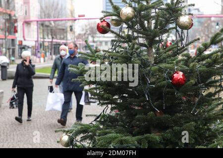 Berlin, Deutschland. Dezember 2020. Fußgänger gehen an einem Weihnachtsbaum in Berlin, der Hauptstadt Deutschlands, vorbei, 16. Dezember 2020. Deutschland wird ab Mittwoch strenger gesperrt, nicht notwendige Geschäfte schließen und die Größe privater Treffen begrenzen, haben sich Bundeskanzlerin Angela Merkel und die Staats- und Regierungschefs der Regionen am Sonntag darauf geeinigt. Die bis Januar 10 in Kraft treten werden, waren eine Reaktion auf ein "exponentielles Wachstum" in der Zahl der COVID-19 Fälle in Deutschland, nach einem Policy Paper. Quelle: ShanYuqi/Xinhua/Alamy Live News Stockfoto