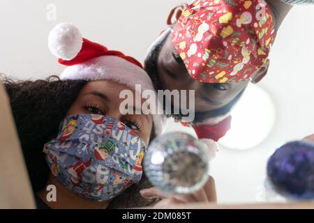 Junges Paar mit Schutzmasken für Coronavirus Öffnen einer Weihnachtsmaterialien, Blick von innen aus der Box. Konzentrieren Sie sich auf Mädchen Gesicht. Stockfoto