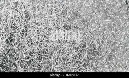 Schwarz-weißer Hintergrund von Aluminium-Späne auf einem Haufen verwickelt. Nahaufnahme von silbrig glänzenden Spiralspänen mit Wellenmuster in abstrakter Textur. Stockfoto