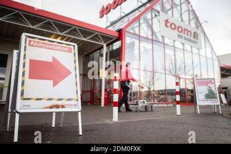 Grevenbroich, Deutschland. Dezember 2020. Ein Toom Hausverbesserungs-Store-Mitarbeiter schiebt einen Warenkorb vorbei am Baumarkt, während ein Schild mit der Aufschrift "Pickup Station" im Vordergrund zu sehen ist. Seit dem 16. Dezember 2020 ist landesweit eine harte Sperre in Kraft. Baumärkte sind jetzt nicht mehr erlaubt, für Wohnkunden zu öffnen, wie sie in der Vergangenheit haben. Vorbestellungen können jedoch noch persönlich abgeholt werden. Quelle: Jonas Güttler/dpa/Alamy Live News Stockfoto