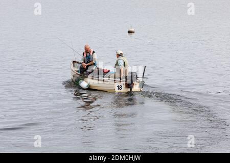 Draycote, Warwickshire, UK - 29/07/20: Zwei männliche Angler in einem kleinen Boot mit einem Außenbordmotor segeln ab, um auf dem Draycote Wasserreservoir zu fischen. Stockfoto