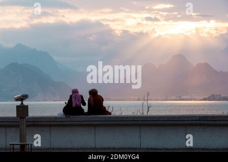 Antalya, Türkei - 22. Februar 2019: Menschen sitzen auf der Steinbrüstungsanlage auf dem Platz der Altstadt Kaleici in Antalya. Stockfoto