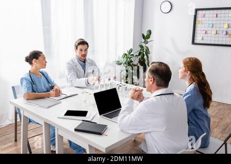 Multikulturelle Ärzte und Krankenschwestern arbeiten mit Papieren und Geräten in Klinik Stockfoto