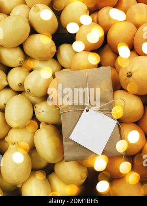 Bunte festliche Geschenk Lieferung Parsel auf gelb und orange strukturierte Zitrushintergrund. Weihnachtsbeleuchtung mit leerem Etikett für Text und Design-Kopie Stockfoto