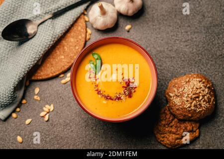 Vegetarische Herbst geröstete Kürbis- und Karottencremesuppe mit Samen und frischen Kräutern in bunten Schalen. Hausgemachte pflanzliche Ernährung Rezept.Low carb und ve Stockfoto