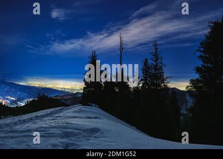 Nachtansicht von den Bergen auf die Stadt, die mit Straßenlaternen leuchtet. Nächtliche Berglandschaft. Ansicht der Stadt Almaty, Kasachstan Stockfoto