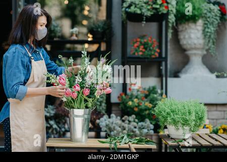 Floristin bei der Arbeit, hübsche junge Frau macht trendige moderne Bouquet von verschiedenen Blumen Stockfoto