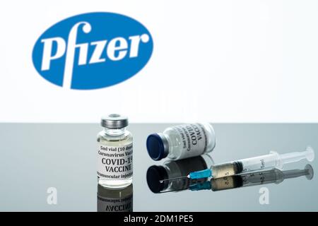 Morgantown, WV - 16. Dezember 2020: Kleine Flasche Coronavirus-Impfstoff mit Spritze mit Hintergrund des Pfizer-Logos Stockfoto