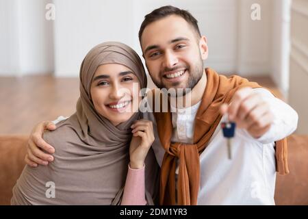 Fröhliche Muslimische Junge Familie Zeigt Den Schlüssel Des Neuen Hauses Im Haus Stockfoto